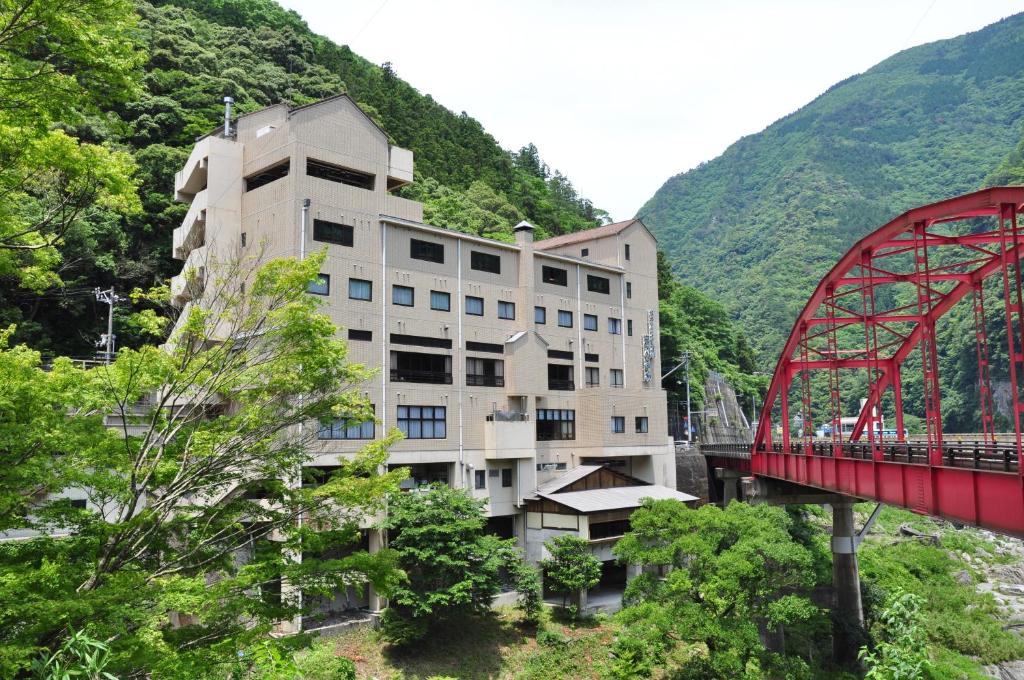 un edificio con un puente rojo junto a una montaña en Obokekyo Mannaka en Miyoshi