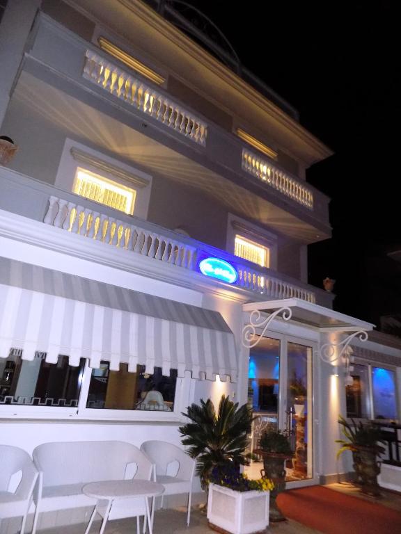 a building with white tables and chairs in front of it at Hotel Residence Villa Del Mare in Rimini