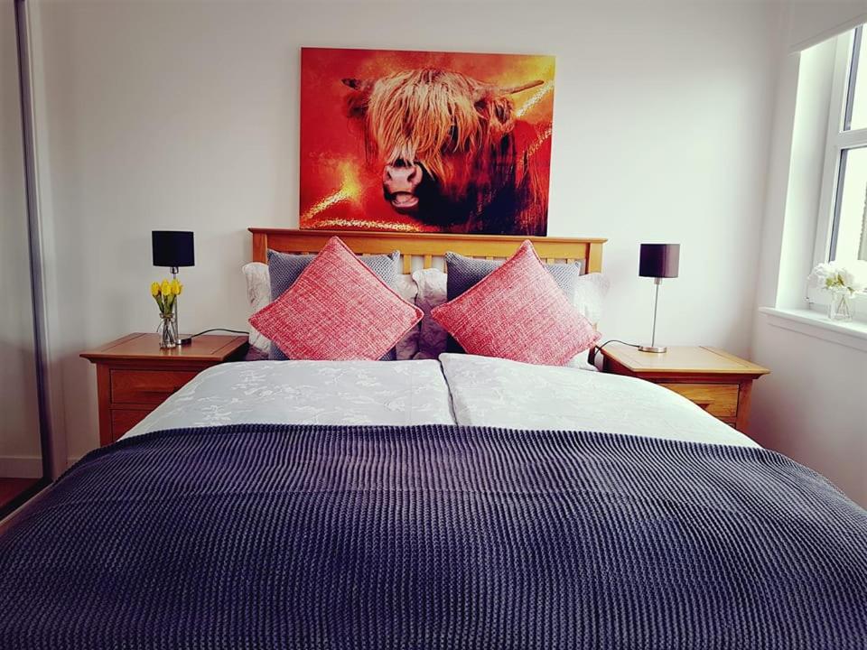 a bedroom with a large bed with pink pillows at Yvi's 2Bedroom 2Bathroom Apartment in Inverurie