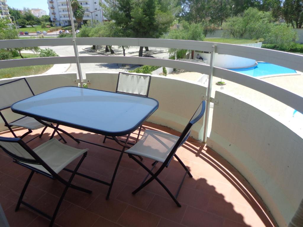 einen Tisch und Stühle auf einem Balkon mit Pool in der Unterkunft T2 50m da Praia in Portimão