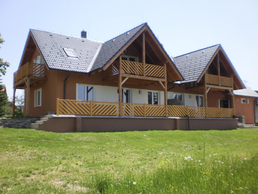 a house with wooden decks and a grass field at Apartmány Eva Frymburk in Frymburk