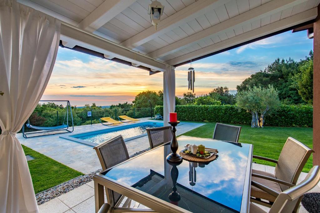 eine Terrasse mit einem Tisch, Stühlen und einem Pool in der Unterkunft Villa Parenzana in Višnjan