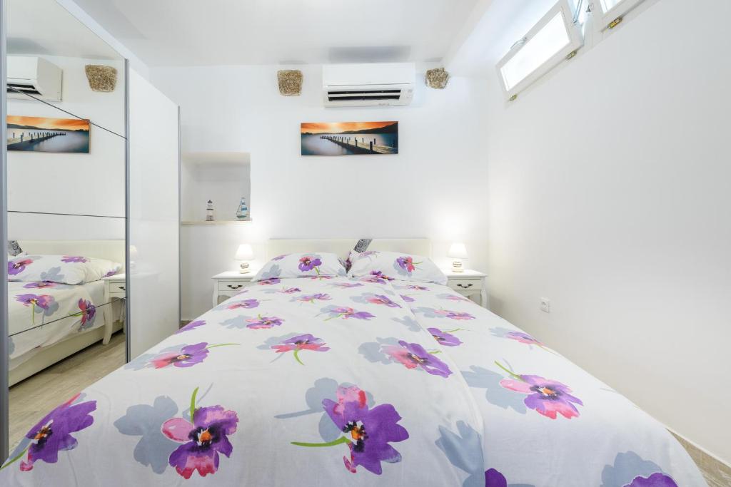biała sypialnia z łóżkiem z fioletowymi kwiatami w obiekcie Lucky Apartment w Dubrowniku