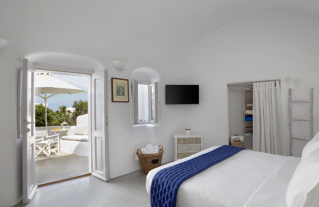 Habitación blanca con cama y balcón. en Naftilos Houses en Oia