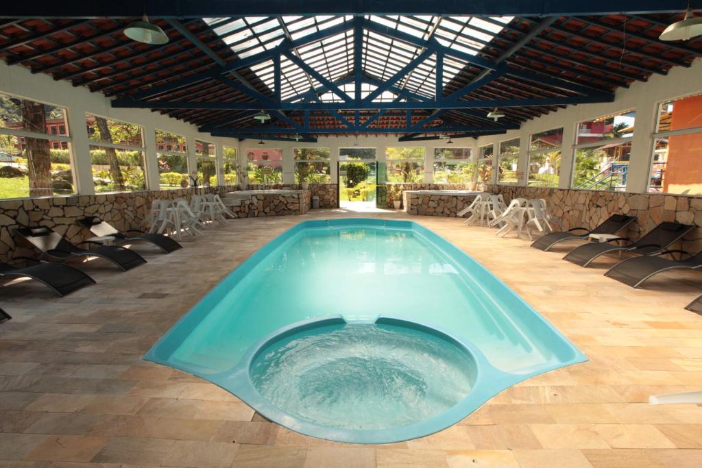 una gran piscina en una habitación con sillas y mesa en Pousada Suarez, en Penedo