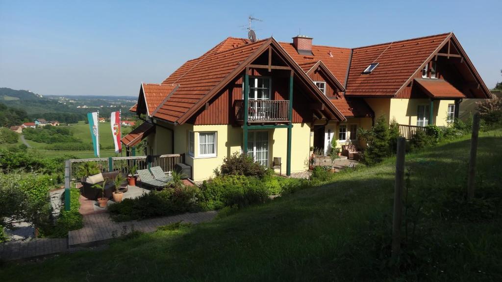 ein Haus mit rotem Dach auf einem Hügel in der Unterkunft Pension Dreiländerblick in Bad Gleichenberg