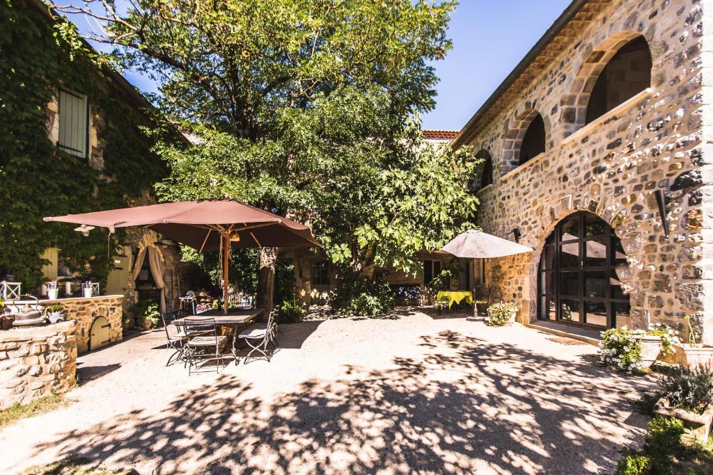 un patio avec des tables et des parasols en face d'un bâtiment dans l'établissement La Flor Azul, à Grospierres