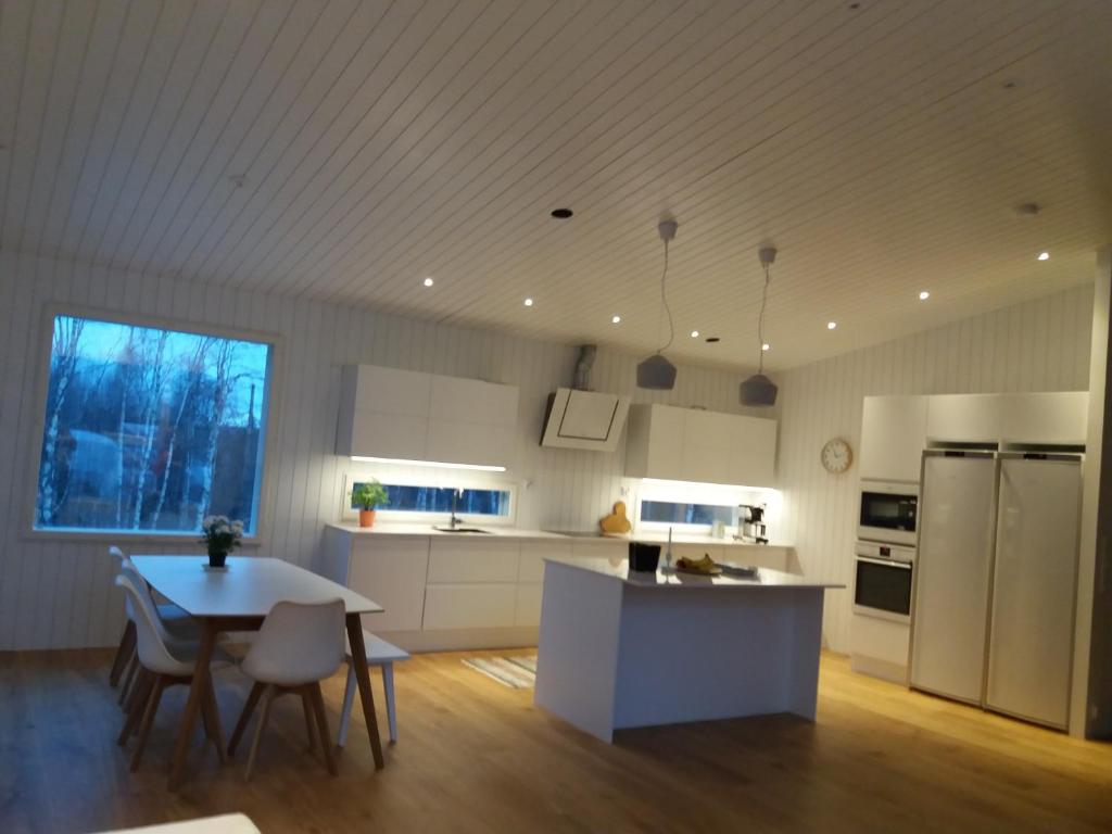ロヴァニエミにあるVilla Ylikyläのキッチン(白い家電製品、テーブル、椅子付)