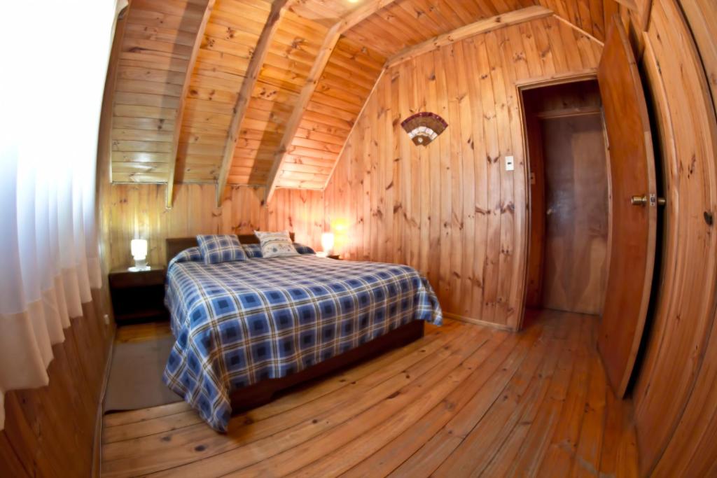 a bedroom with a bed in a wooden cabin at Cabañas Diquen's El Tabo in El Tabo