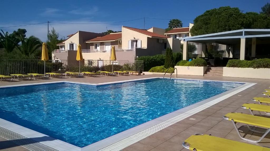 uma piscina com cadeiras e guarda-sóis num resort em Marinos Apartments em Lassi