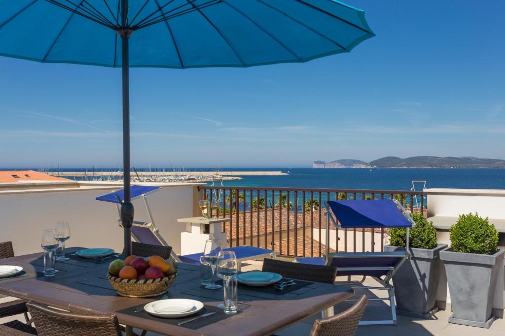 un tavolo con ombrellone su un balcone con vista sull'oceano di Fiore Penthouse ad Alghero