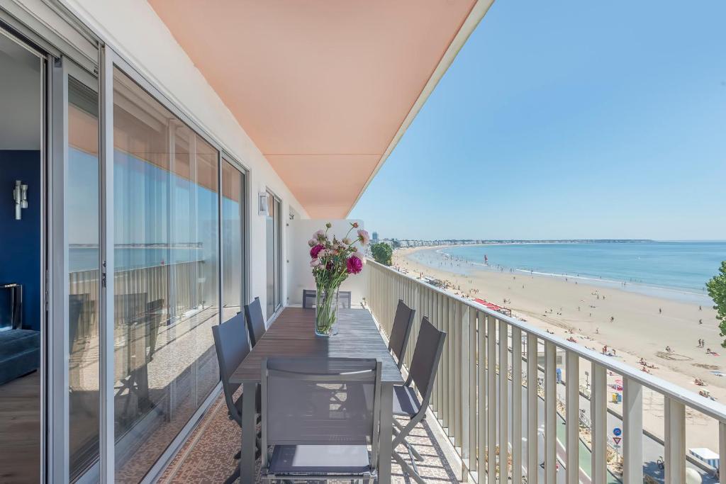 einen Balkon mit einem Tisch und Stühlen sowie Strandblick in der Unterkunft Vue sur mer La Baule "Victoria" in La Baule