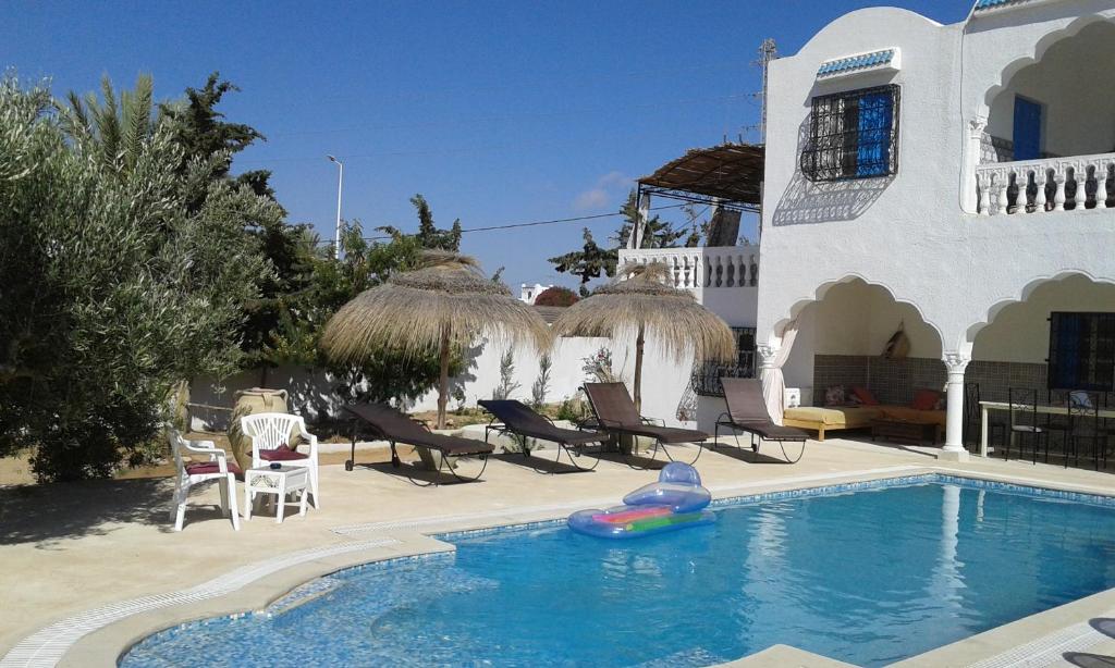 a swimming pool with a inflatable raft in front of a house at Menzel Churasco Djerba in Aghīr