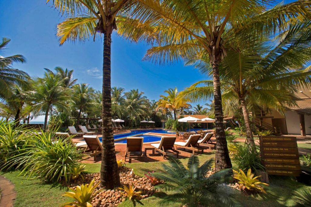 a resort with a pool and chairs and palm trees at Bupitanga Hotel in Pipa