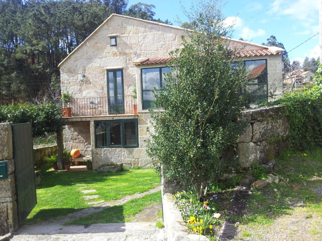 una vieja casa de piedra con un árbol delante en Casa do Crego en Vilaboa