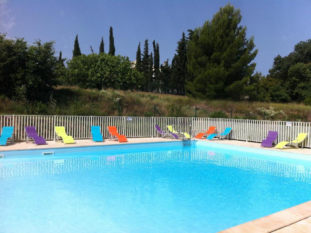 een zwembad met kleurrijke stoelen en een hek bij Zenitude Hôtel-Résidences Toulon Six Fours in Six-Fours-les-Plages