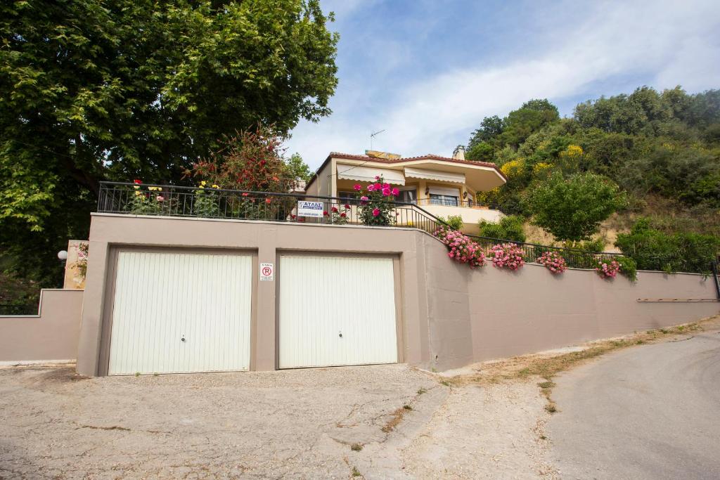 dwa drzwi garażowe przed domem z kwiatami w obiekcie Chita's House w mieście Paralia Vrachou