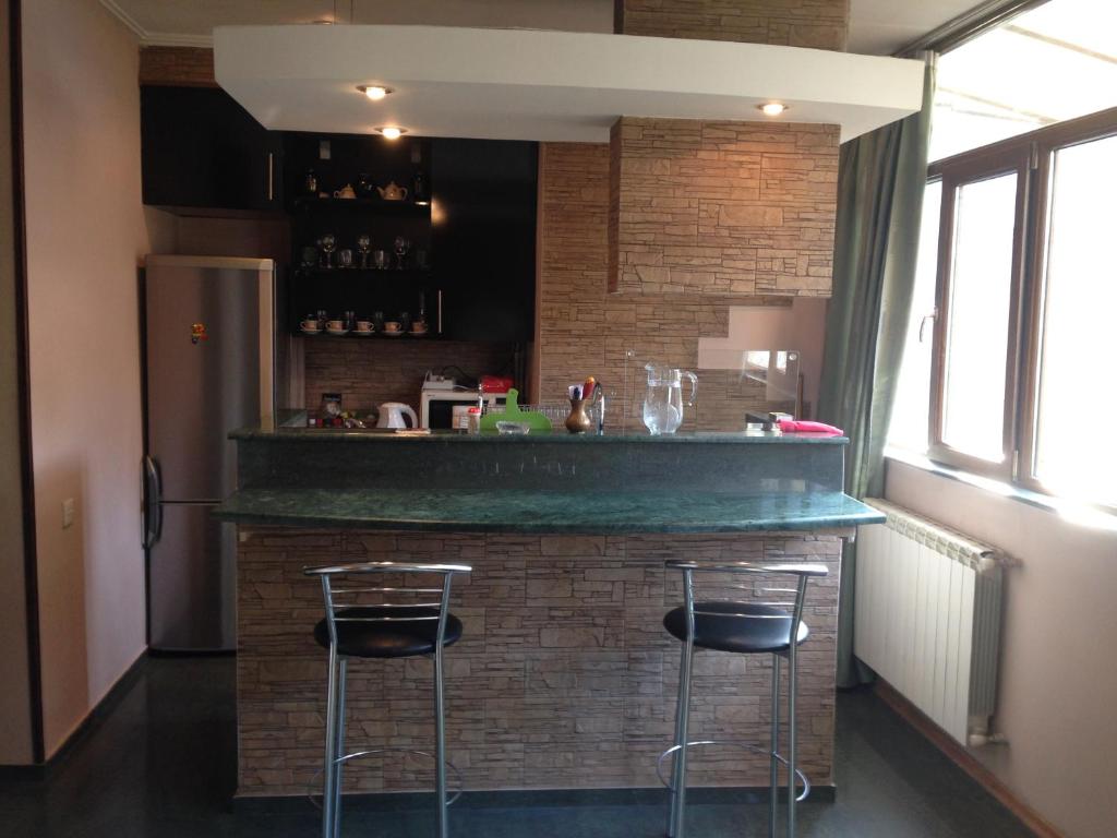 a bar with two stools in a kitchen with a brick wall at Apartment on Sanapiro in Tbilisi City