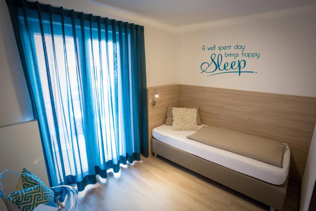 a small bedroom with a bed with blue curtains at Hotel Landgasthof zum Kaffelstein in Kreuzwertheim