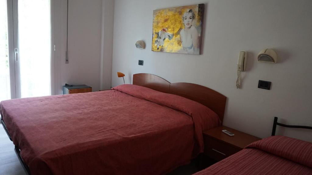 リミニにあるHotel Dariaのベッドルーム1室(赤いシーツを使用したベッド2台付)