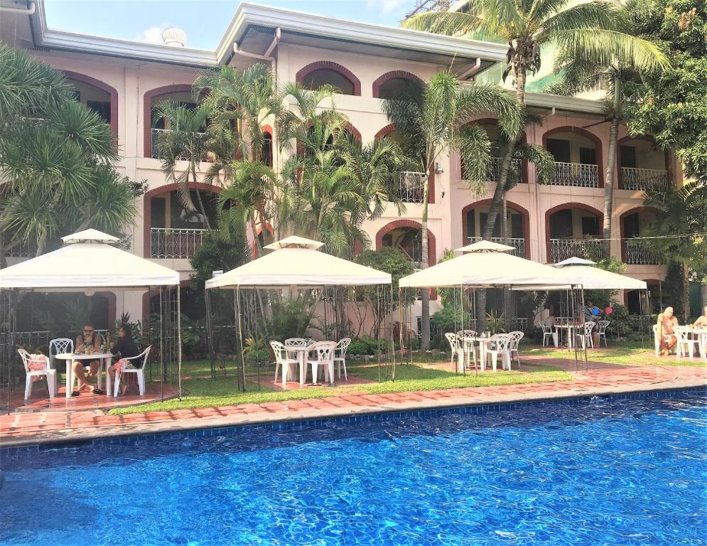 a hotel with tables and umbrellas next to a swimming pool at Orchid Inn in Angeles