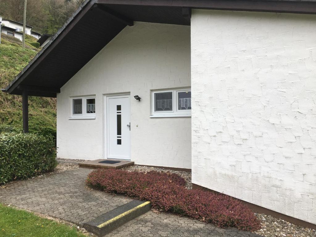 uma casa branca com uma porta branca e um alpendre em Ferienhaus Stausee Bitburg em Biersdorf