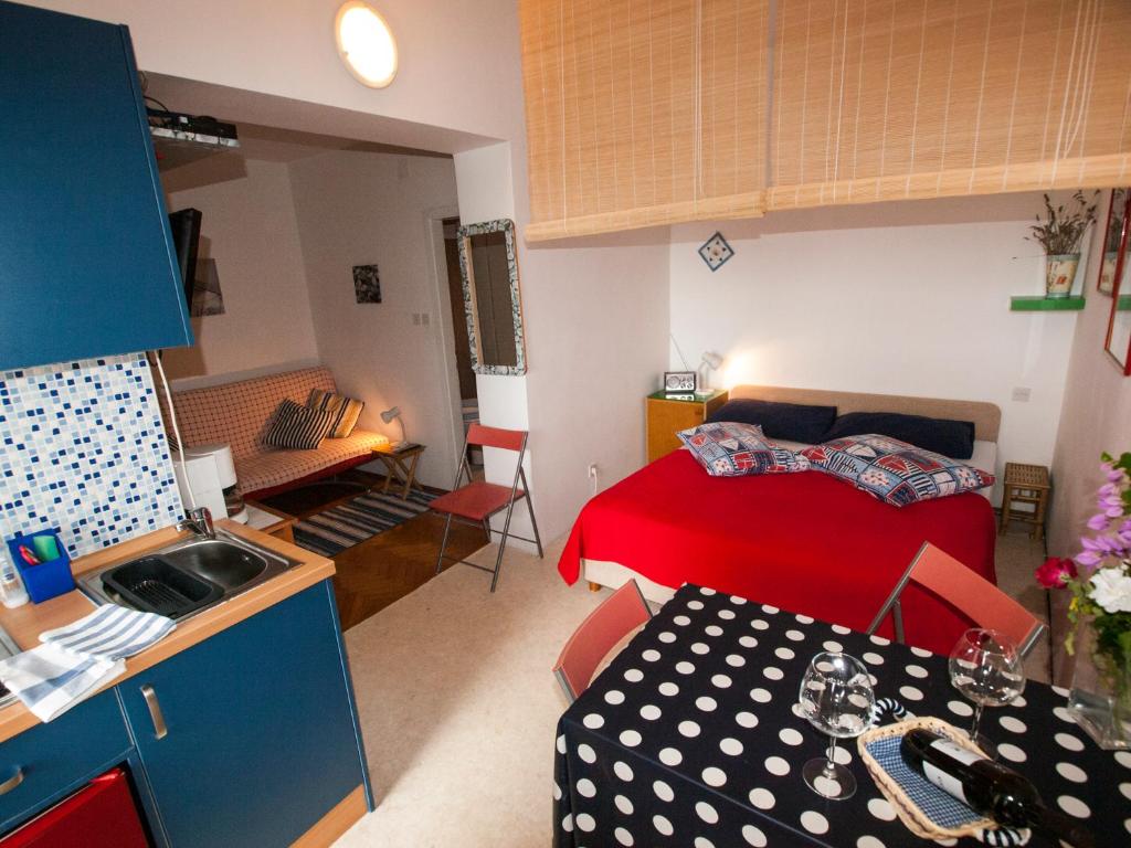 a small room with a red bed and a kitchen at Apartments Barka in Tučepi