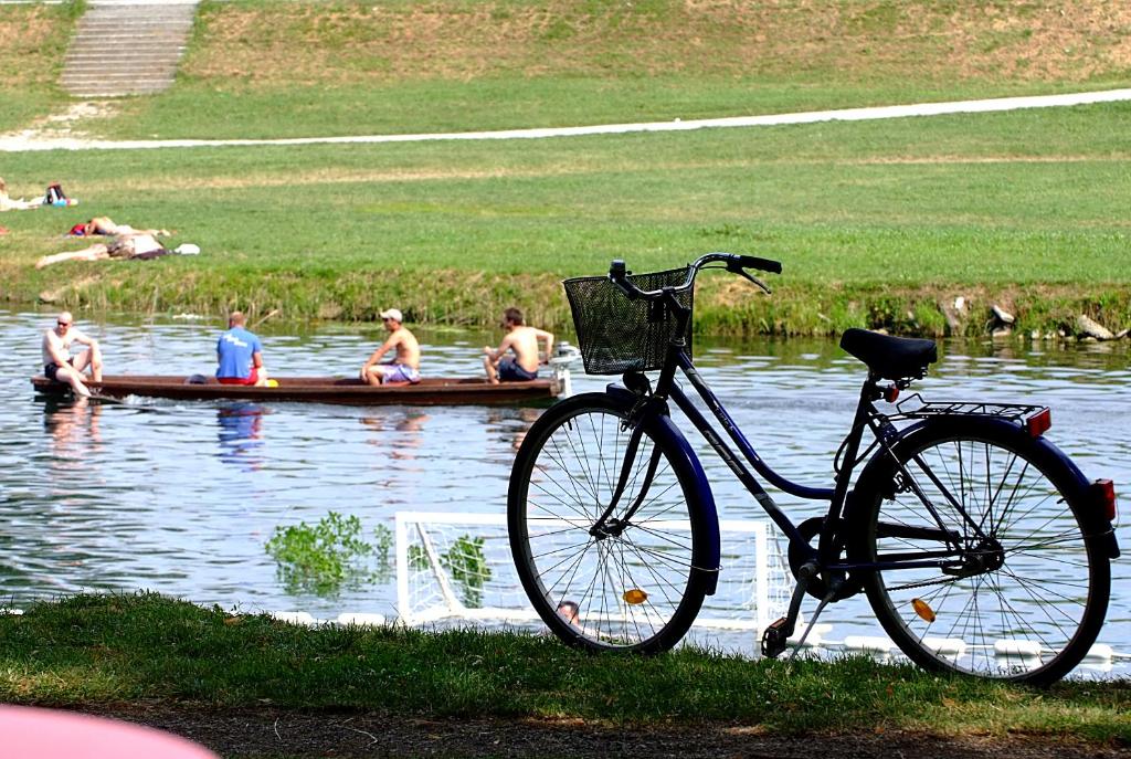 ein Fahrrad, das neben einem Wasserkörper parkt, mit Menschen in einem Boot in der Unterkunft Apartment Karlovac in Karlovac