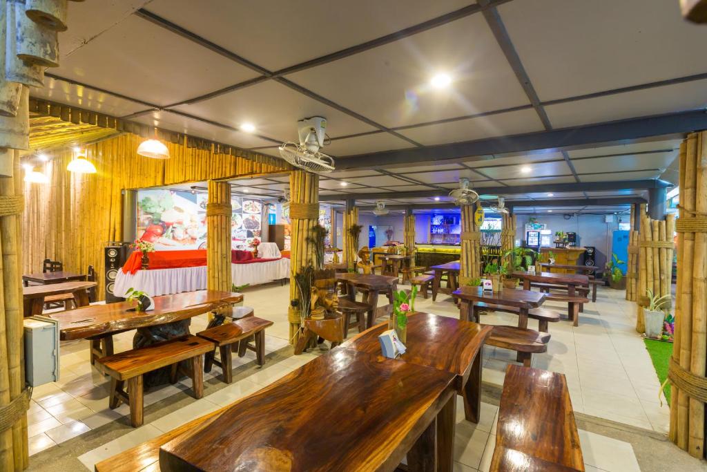 a restaurant with many wooden tables and benches at Sunrise Resort- Koh Phangan - SHA Extra Plus in Haad Rin