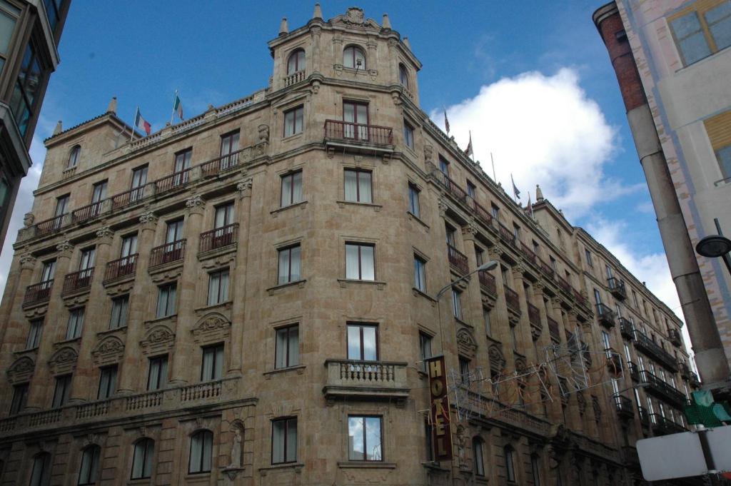 Un edificio alto con una torre dell'orologio sopra. di Hotel Monterrey a Salamanca