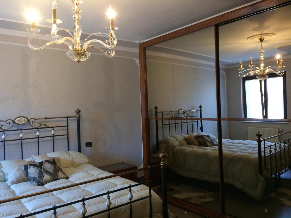 een slaapkamer met 2 bedden, een spiegel en een kroonluchter bij Sicily Center rooms in Calascibetta