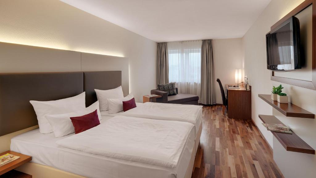 una camera d'albergo con letto e TV di Hotel Newton Heilbronn a Heilbronn