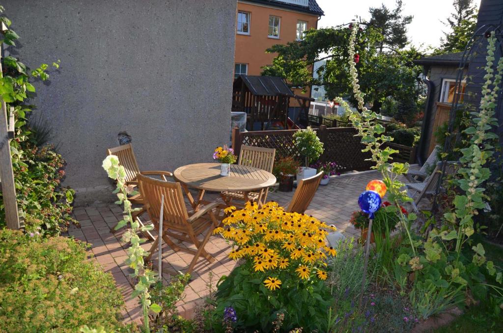 a patio with a table and chairs and flowers at Ferienwohnungen Chris Stephan in Oberweißbach