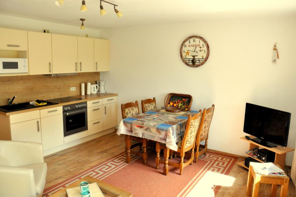 een keuken met een eettafel met stoelen en een klok bij Ferienhaus Erholung Pur in Boltenhagen