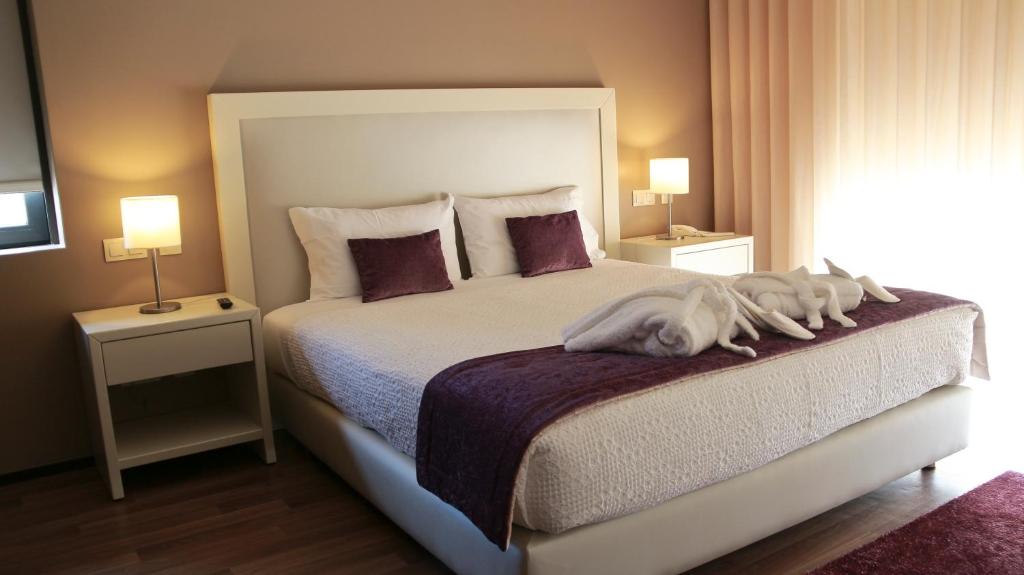 a white dog laying on top of a bed at Hotel Monte Lírio in Espinho