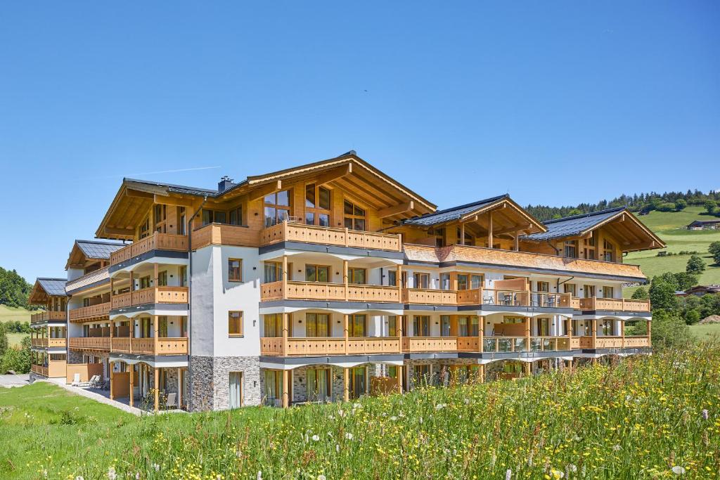 ein großes Gebäude auf einem Hügel mit einem Feld in der Unterkunft Residenz Drachenstein Wildschönau in Niederau