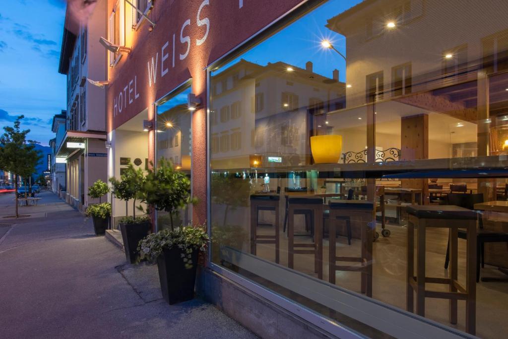 a restaurant window with tables and chairs in a street at Hotel Weiss Kreuz in Thusis