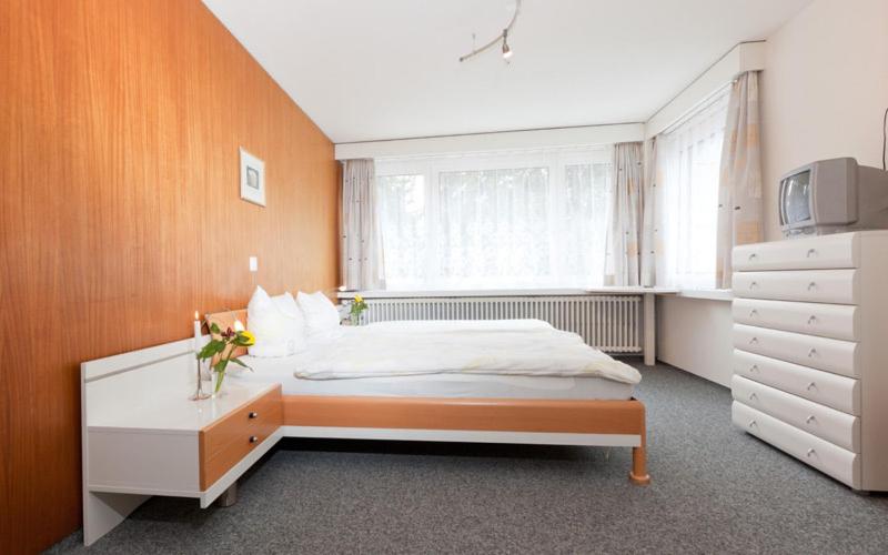 Hotel Piz Badus في أندرمات: غرفة نوم مع سرير وخزانة ونافذة