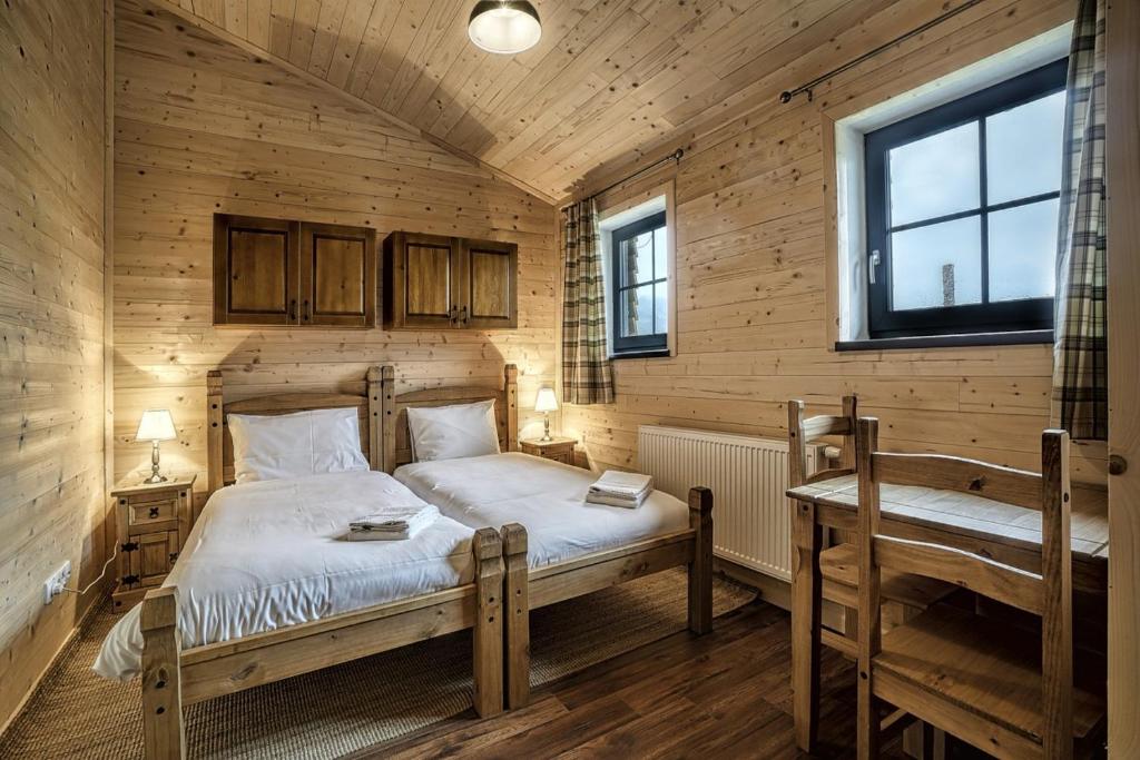 a bedroom with two beds and a table and two windows at Belianska Chata in Ždiar