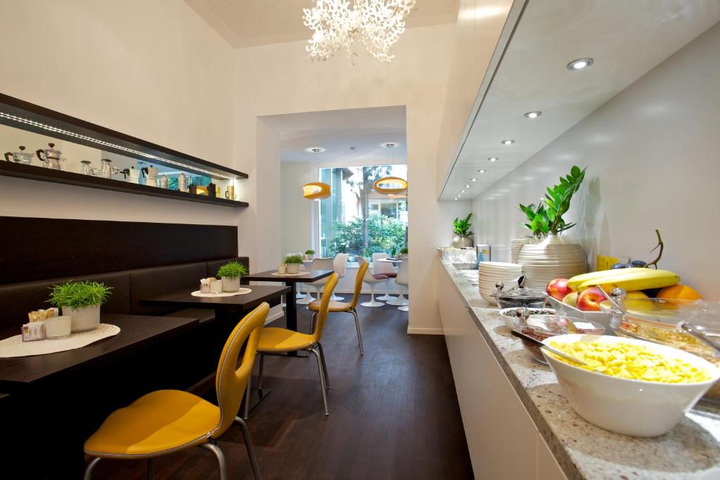 un restaurant avec des chaises jaunes et un comptoir avec de la nourriture. dans l'établissement Boutique Hotel Imperialart, à Merano