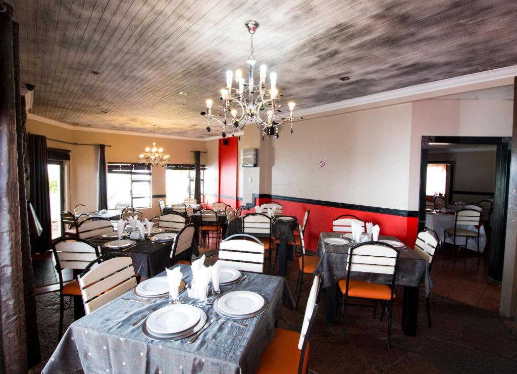 uma sala de jantar com mesas e cadeiras e um lustre em The Shamrock Hotel em Polokwane