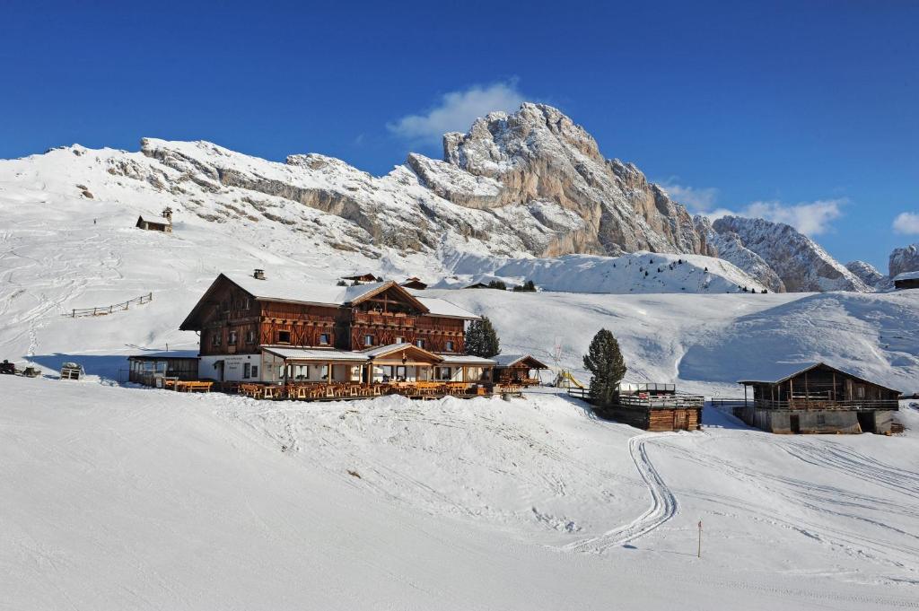 a large building in the snow with a mountain at Rifugio Fermeda Hutte in Santa Cristina in Val Gardena