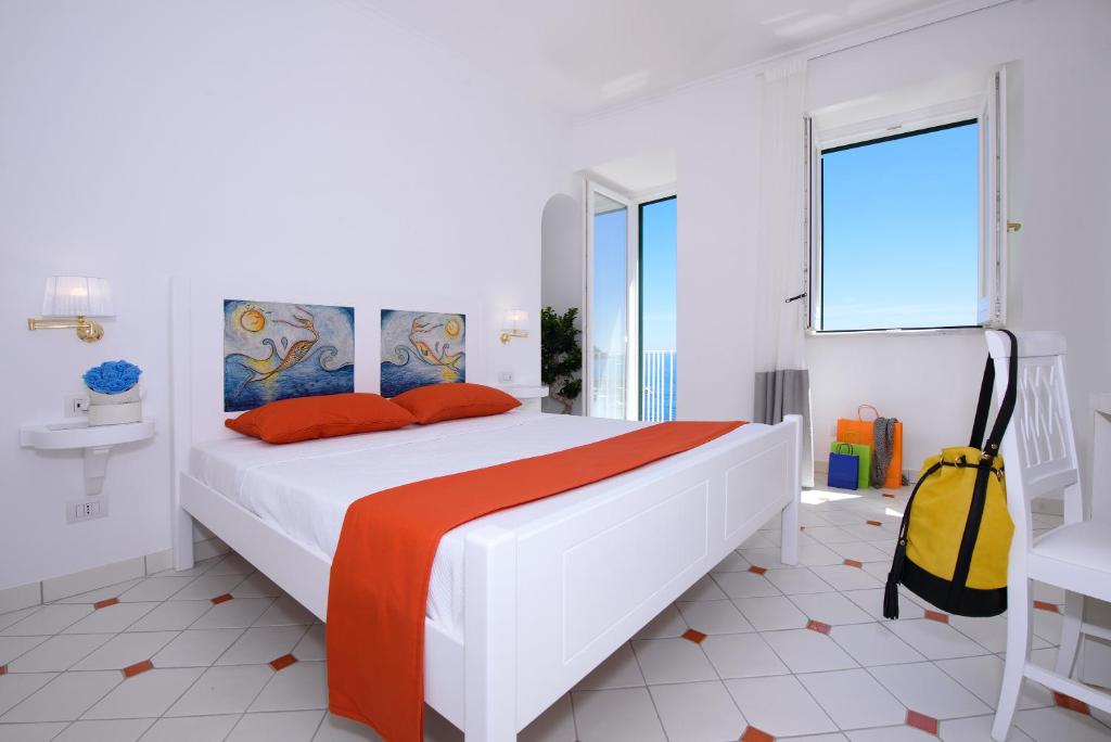 a white bedroom with a large bed with orange pillows at Vista d'Amalfi in Amalfi