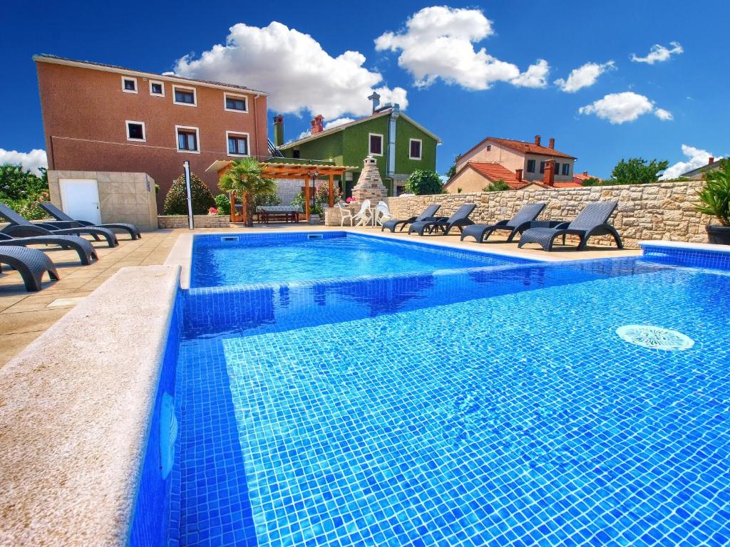 uma piscina com cadeiras ao lado de um edifício em Apartments Mile 1249 em Fažana