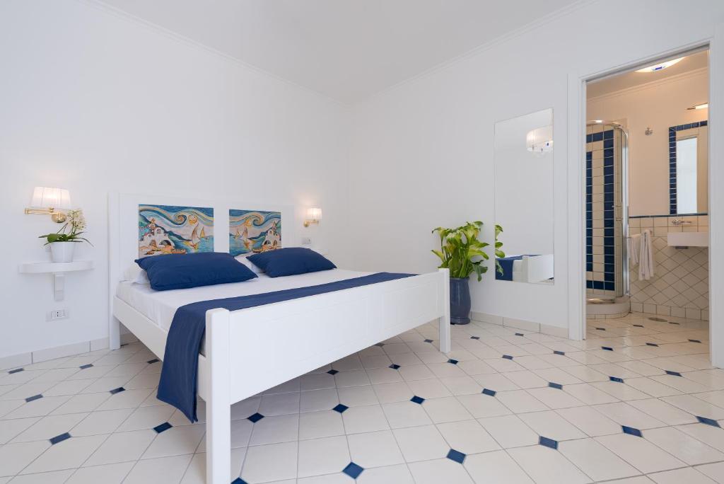 a white bedroom with a bed with blue pillows at Vista d'Amalfi in Amalfi