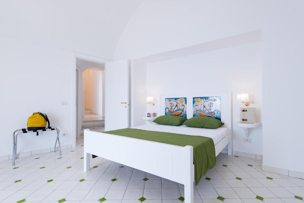 a white bedroom with a large bed with green sheets at Vista d'Amalfi in Amalfi