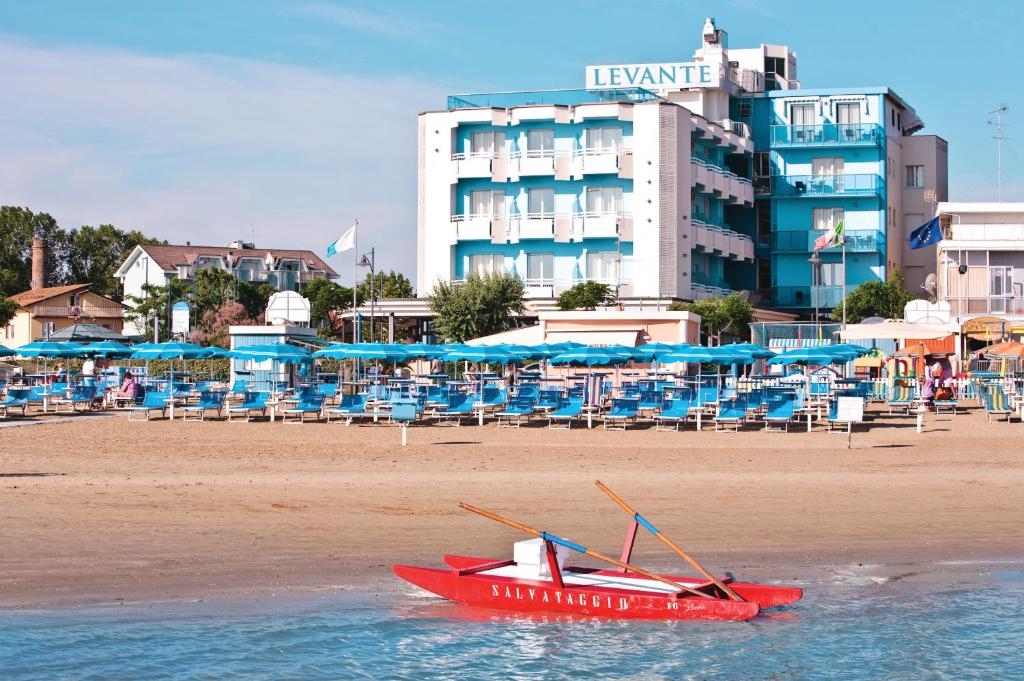 ein rotes Boot im Wasser neben einem Strand in der Unterkunft Hotel Levante in Bellaria-Igea Marina