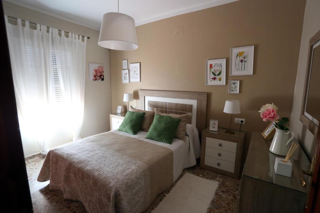 a bedroom with a bed with green pillows and a window at Apartamento Duque de Arcos in Arcos de la Frontera