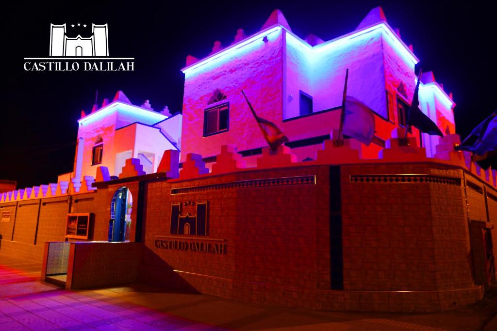 a building is lit up in pink and purple at Castillo Dalilah in Tan-Tan Plage