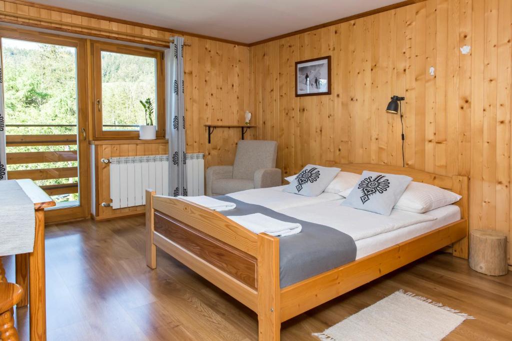 sypialnia z łóżkiem w pokoju z drewnianymi ścianami w obiekcie udanypobyt Pokoje Klemensówka w Zakopanem